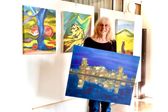 Frau Ute Koch mit einem Bild das eine Stadt bei Nacht zeigt die sich in wasser spiegelt