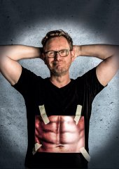 Bild zeigt Martin Sierp mit einem auf das T-Shirt geklebten Foto von einem Six-Pack