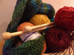 Bild zeigt verschiedenfarbige Wollknäule und Stricknadeln