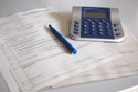 Ein Taschenrechner und Kugelschreiber auf einem Antragspapier.