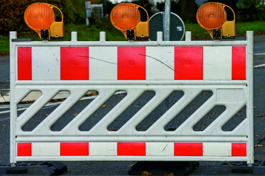 Das Bild einer Strassensperre mit 3 Orangen Blinklichtern oben drauf.