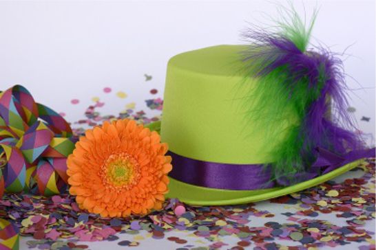 Ein grüner Zylinder und eine orangene Blume mit Konfetti und Luftschlangen