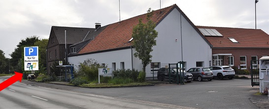 Ein Foto des Gebaudes des DLB mit einem Pfeil auf den Parkplatz