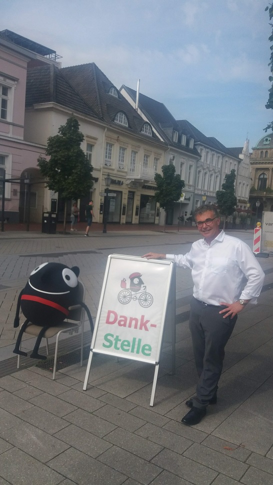 Bürgermeister Heide neben dem Schild Dankstelle