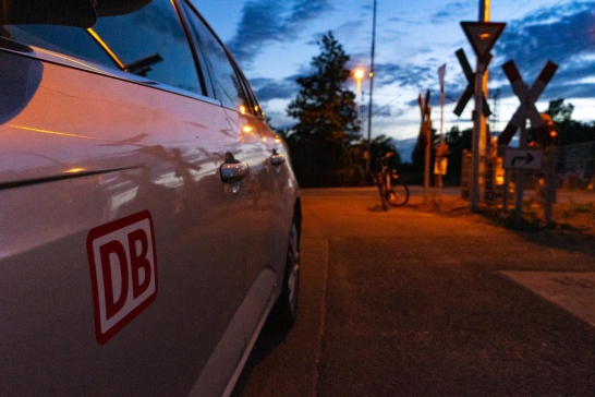 Ein Bahnübergang bei nacht mit einem DB auto davor