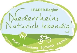 Der Schriftzug "Leader Region Niederrhein Natürlich lebendig!" vor einem weißen Fahrrad auf einer Grünen Wiese