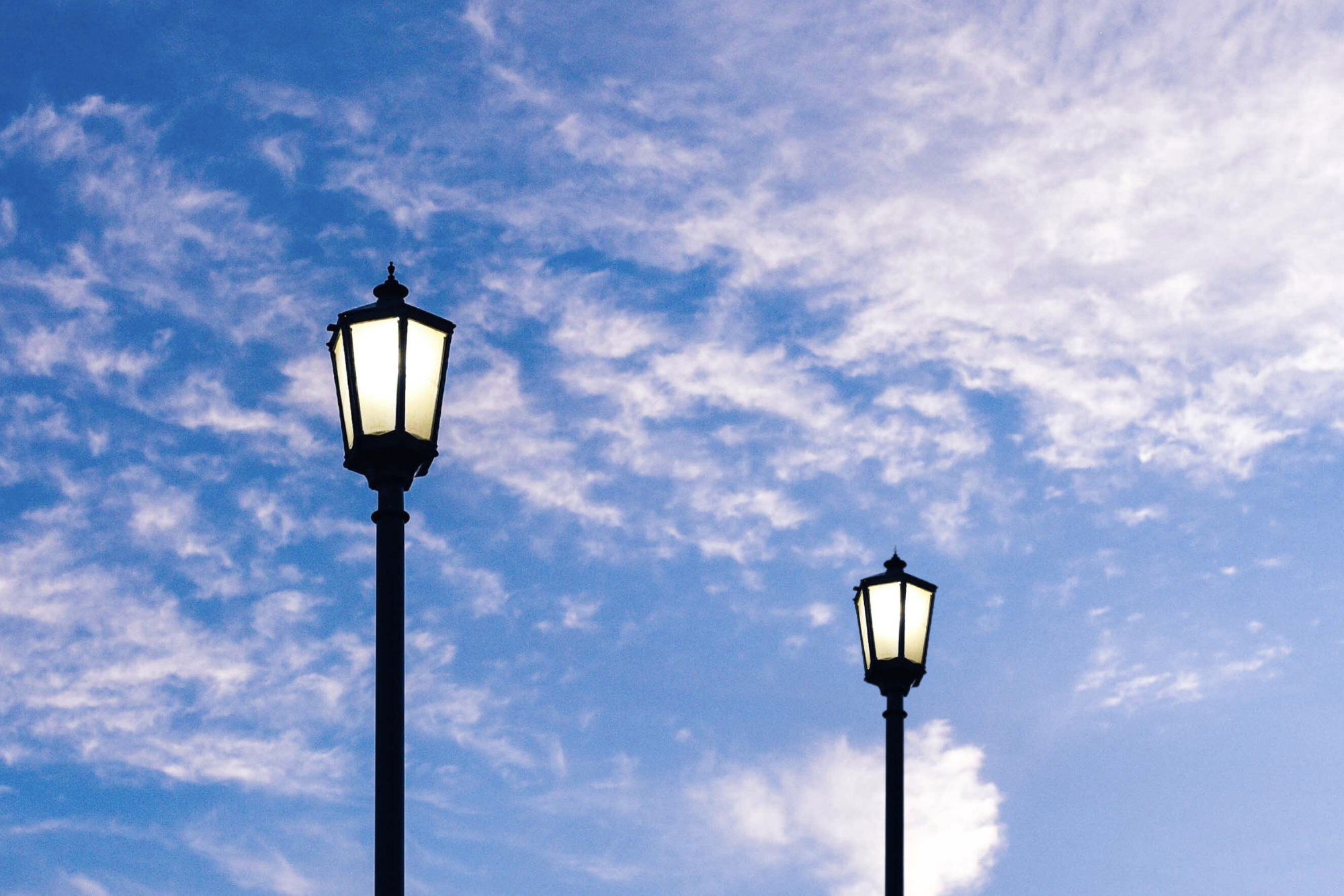 2 Strassenlaternen vor einem blauen Himmel
